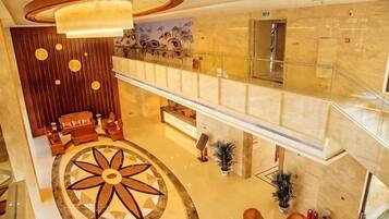 A hotel lobby with a central circular design, a reception desk, and a staircase leading to an upper level.