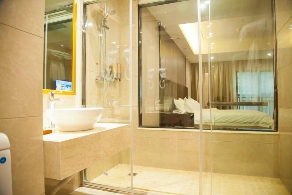 A modern bathroom with a glass-enclosed shower, a white sink, and a large mirror.