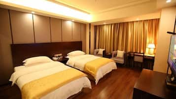 A hotel room with two beds, a desk, a chair, a TV, and a curtain.