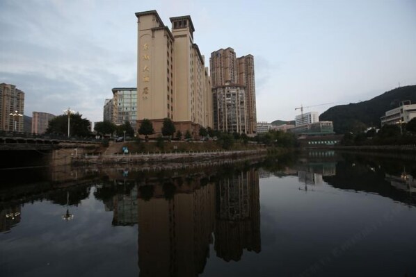 A high-rise building with a reflective water body in front. - Donghu Hotel (Shouning)