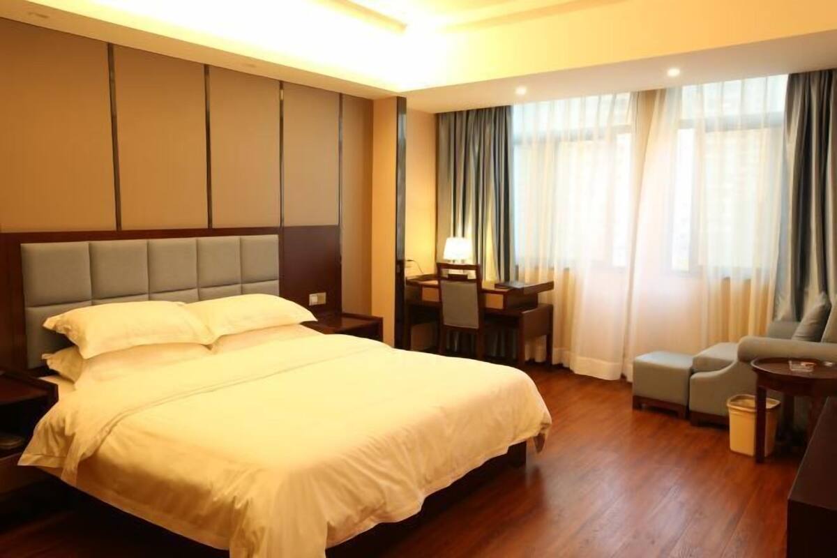 A hotel room with a bed, a desk, a chair, a sofa, and a small table.