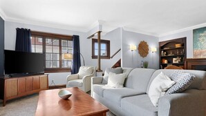 Ein Wohnzimmer mit Sofa, Couchtisch, Fernseher und Bücherregal.