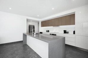 Una cucina moderna con isola centrale, mobili bianchi e pavimento scuro.