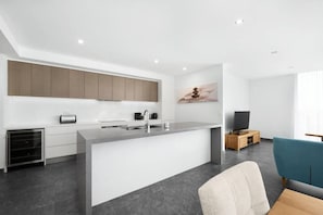 Enjoy a spacious kitchen with a large island, sink, and coffee machine, plus a comfortable seating area with a flat-screen TV.