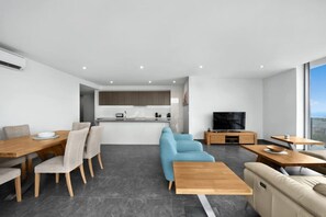 Relax in this open-plan living space with a dining table, sofa, and TV, offering a view of the outdoors.