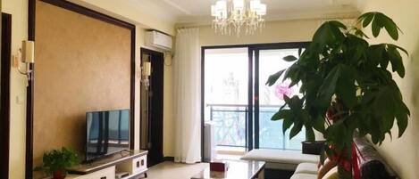 Un salon comprenant un grand téléviseur à écran plat, un canapé, une table basse et une plante en pot.