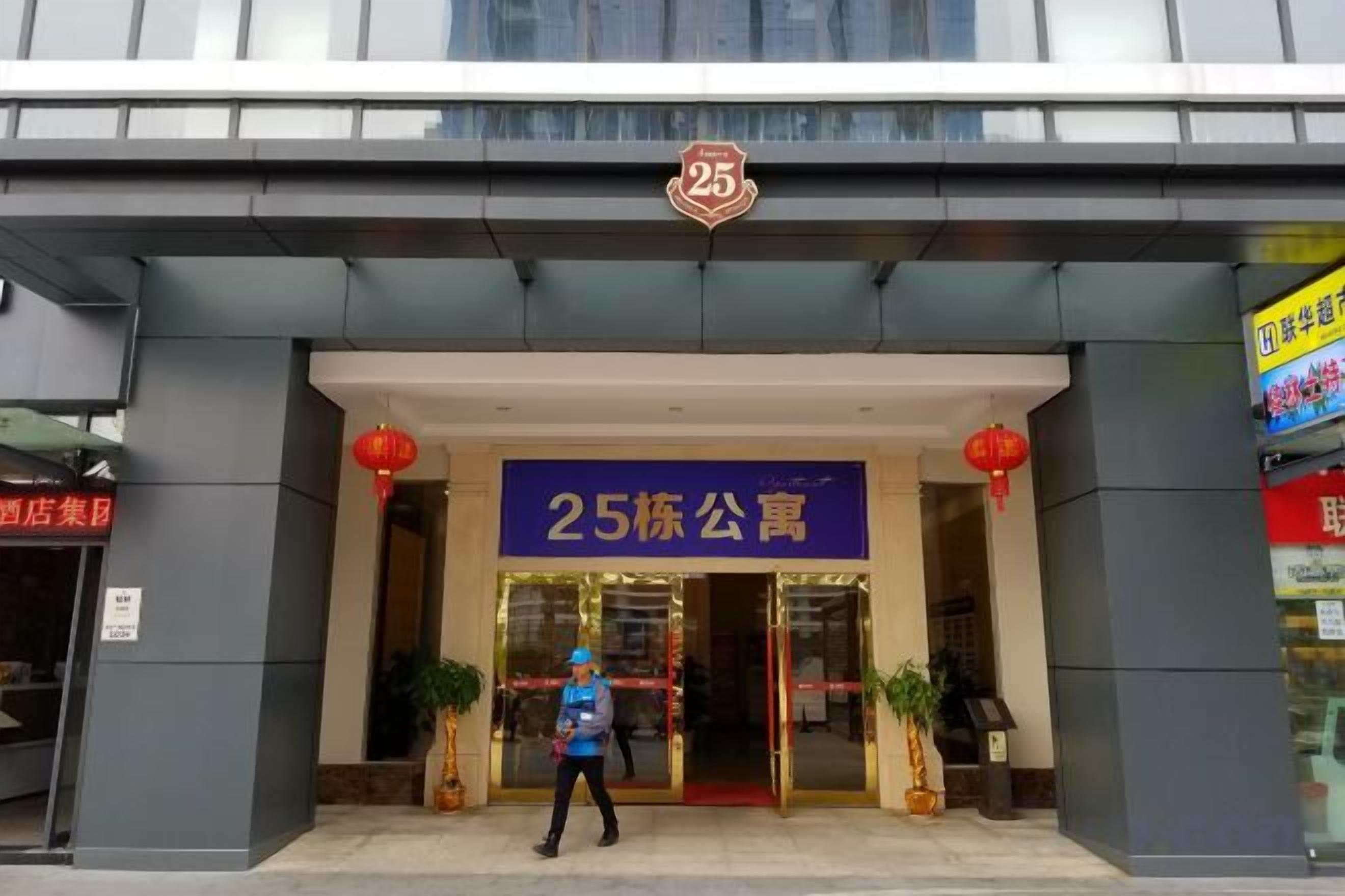 A hotel entrance with a prominent sign, a person standing in front, and potted plants.