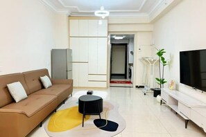 Uma sala de estar moderna com um sofá, uma televisão, uma mesinha e um tapete decorativo.