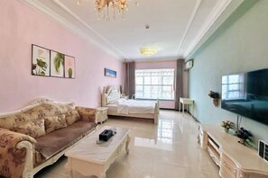 Una habitación con cama, sofá, televisión y candelabro.