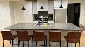 A modern kitchen with a large island, white cabinets, stainless steel appliances, and pendant lighting. - 4 Season Fun on Lake Namakagon - Snowmobiling, Boating, Fishing, UTV & More! (Cable)