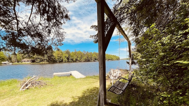 A wooden swing hanging from a tree, a wooden dock extending into a lake, and a grassy area with dense foliage. - 4 Season Fun on Lake Namakagon - Snowmobiling, Boating, Fishing, UTV & More! (Cable)