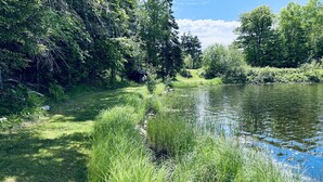 A serene riverside landscape with lush greenery and a small wooden structure. - 4 Season Fun on Lake Namakagon - Snowmobiling, Boating, Fishing, UTV & More! (Cable)