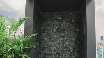 A modern shower with a tiled wall and a visible showerhead.
