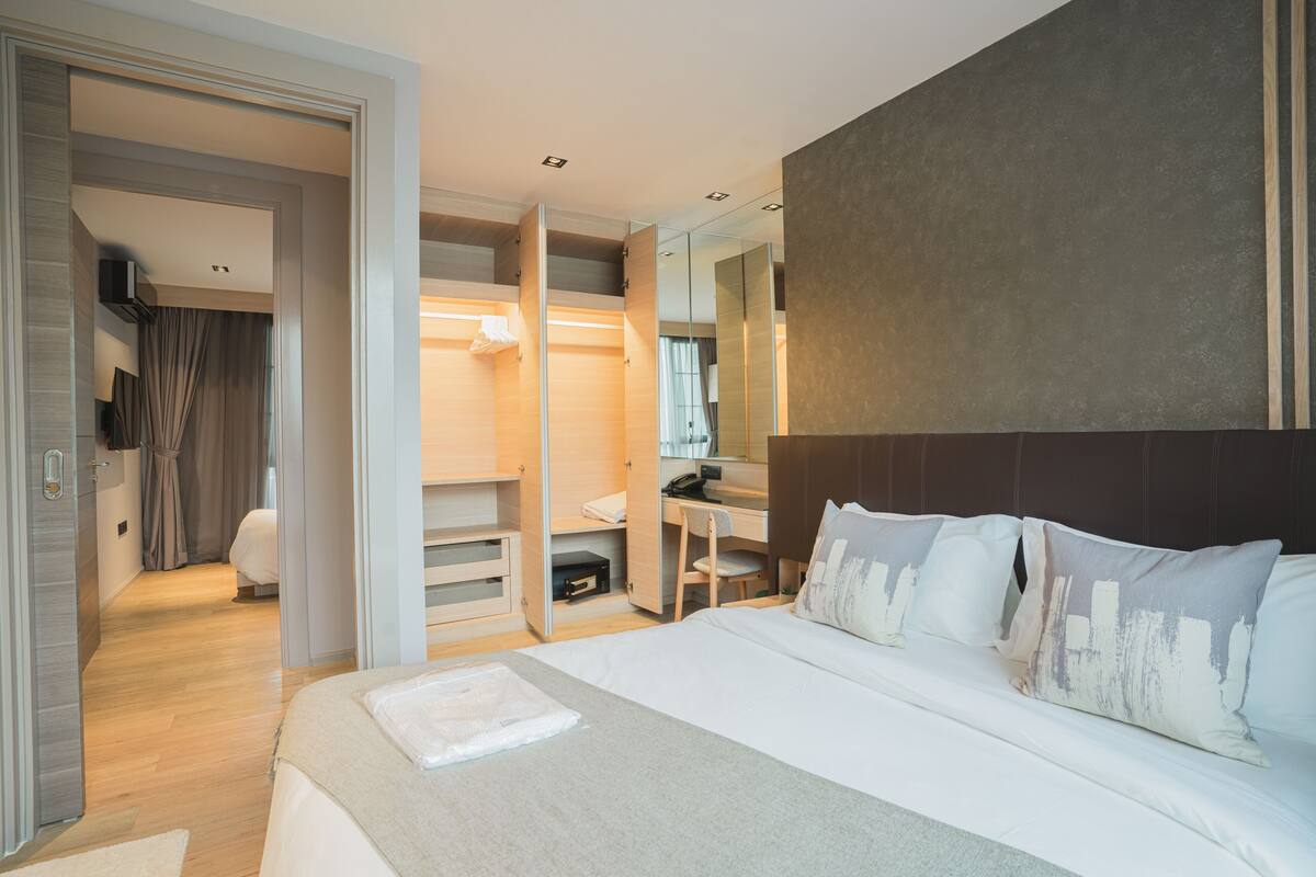 Quarto de hotel moderno com uma cama grande, uma escrivaninha e um closet espaçoso.