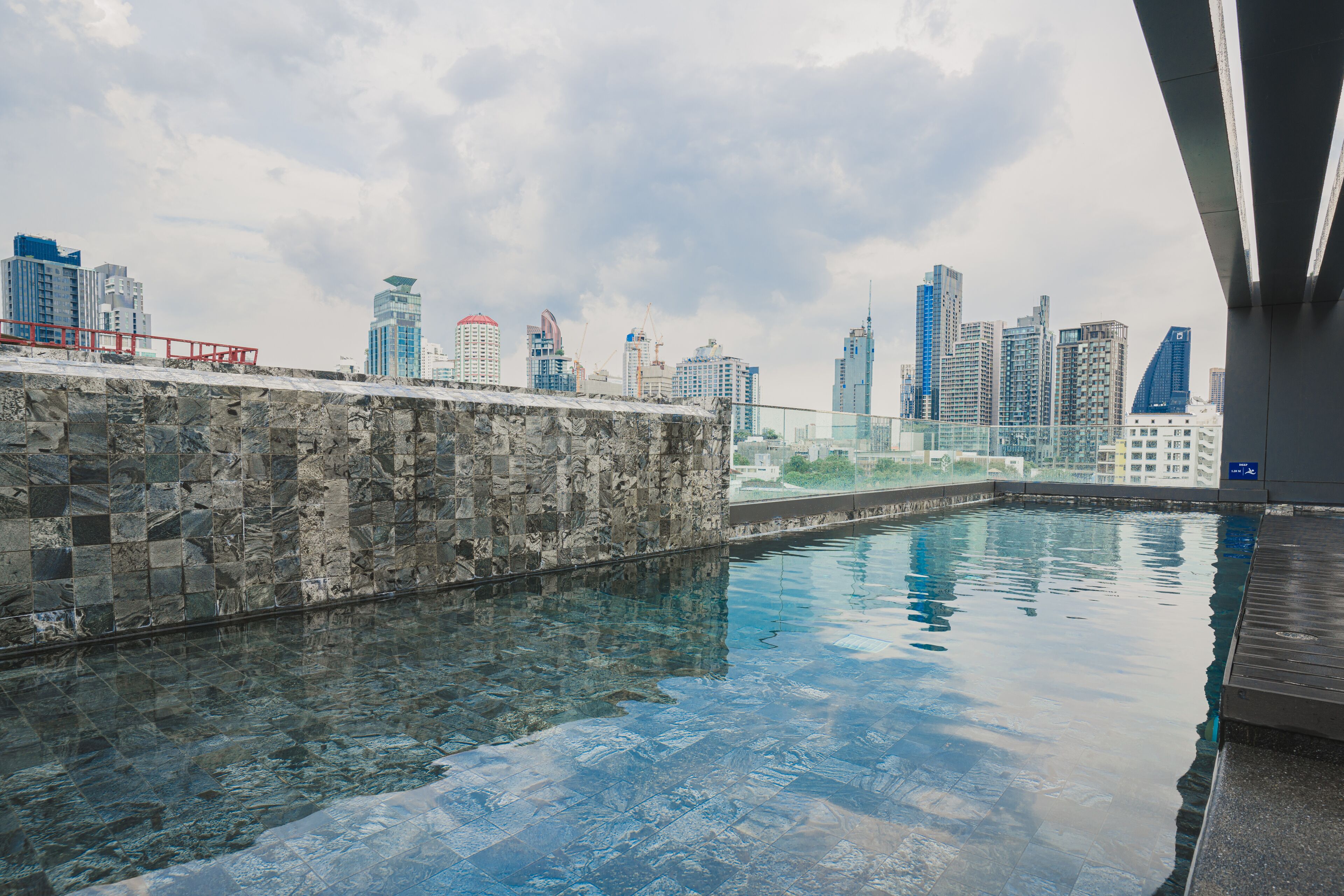 An indoor swimming pool with a cityscape view, stone walls, and a modern architectural design.