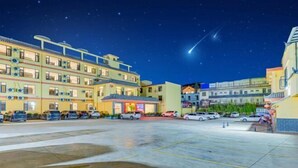 Un hotel de varios pisos con un estacionamiento y varios automóviles.