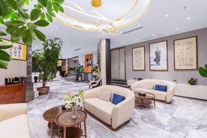 Un moderno hall de hotel con zonas de estar, un mostrador de recepción y una escalera que conduce a otras plantas.