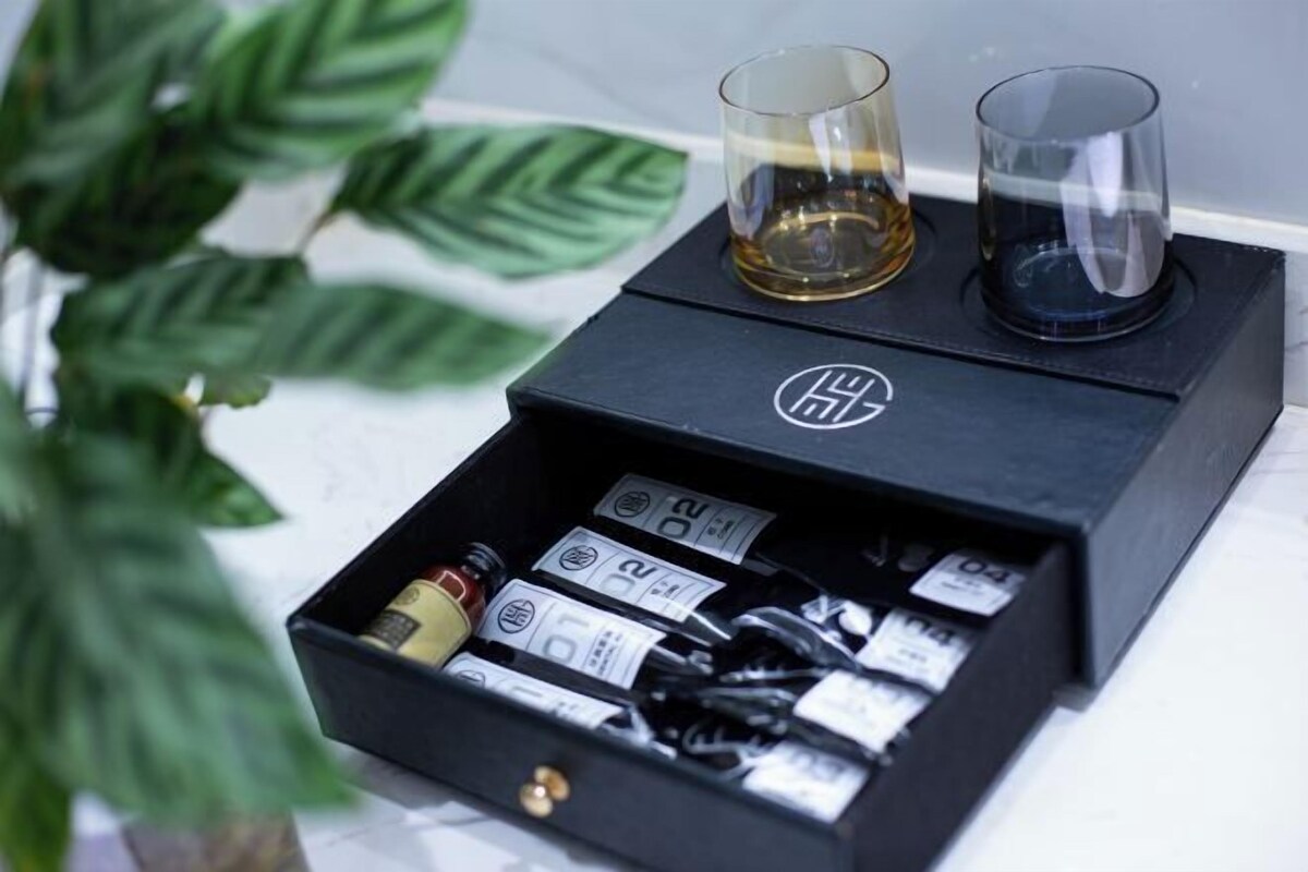 A black box with a logo, two glasses, and a drawer containing various items.