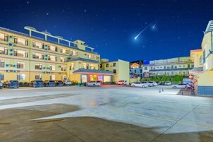 Un hotel de varios pisos, con estacionamiento y un cielo despejado.