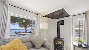 A cozy living room with a sofa, a fluffy cushion, a lamp, and a wood-burning stove. - Welcome to Lake House On Park (Yarker)