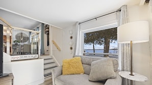 A cozy living area with a sofa, a lamp, and a window with a view of the lake. - Welcome to Lake House On Park (Yarker)