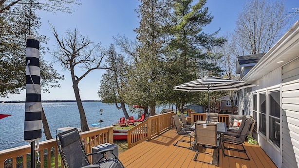 A deck with outdoor furniture, a striped pole, and a view of the water. - Welcome to Lake House On Park (Yarker)