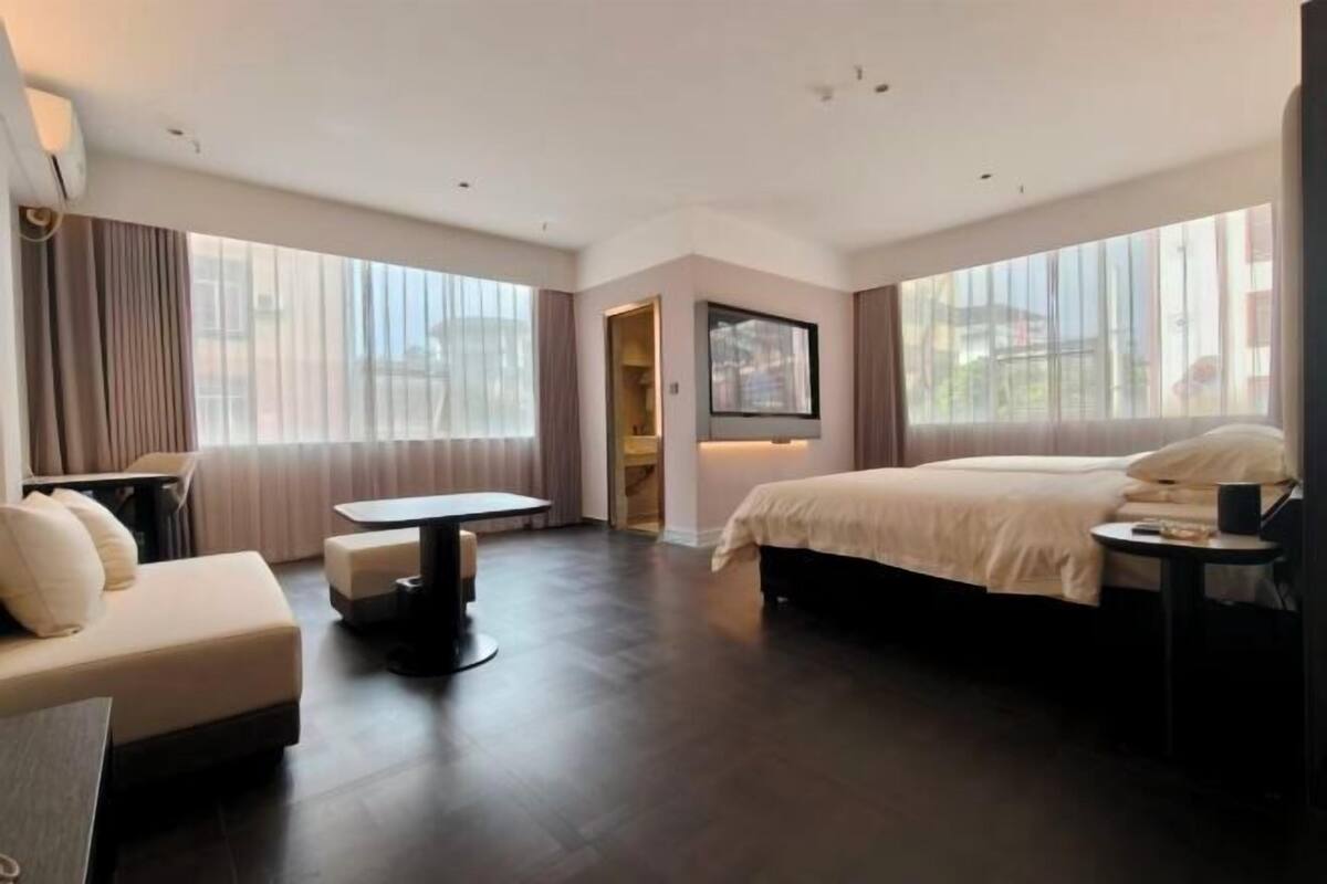 Una habitación de hotel moderna con una cama grande, un sofá, una mesita y un escritorio.