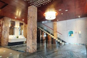 A spacious lobby with a marble column, a staircase, and a modern chandelier. - Jin Ting Hotel (Shanglin)