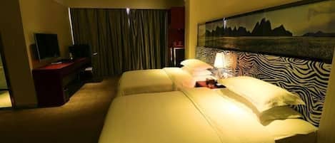 A hotel room with a large bed, a desk with a television, and a painting on the wall.