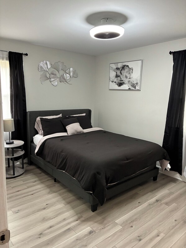 A bedroom with a bed, a round table, a wall art piece, and a ceiling light. - The Welcoming Winston | 3BR Cozy Home & Pool Table (Winston-Salem)