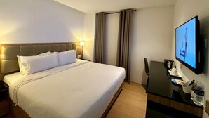 A hotel room with a bed, a desk, a chair, a television, and curtains. - D Loft Hotel (Kuala Lumpur)