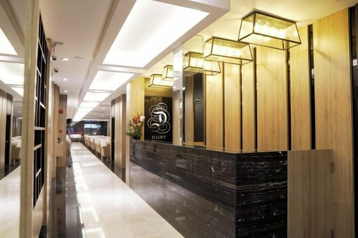 A hotel reception area with a marble counter, wooden paneling, and modern pendant lighting.