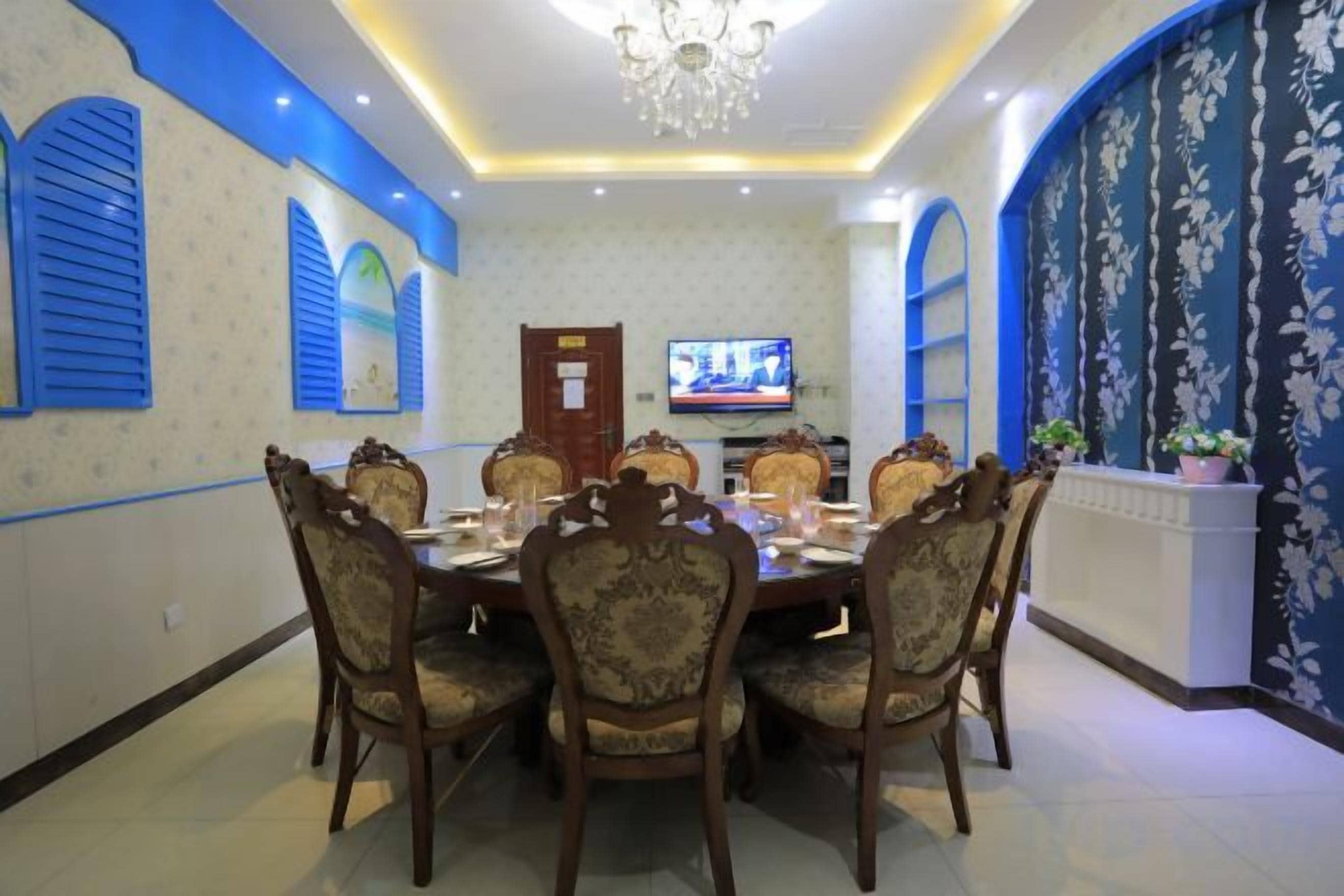 A dining area with a round table, chairs, and a television on the wall.