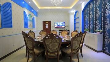 A dining area with a round table, chairs, and a television on the wall.