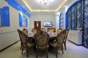 A dining area with a round table, chairs, and a television on the wall.
