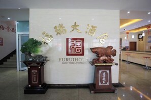 A reception area with a sign for Furuihotel, featuring a traditional Chinese design with calligraphy and a lion statue.