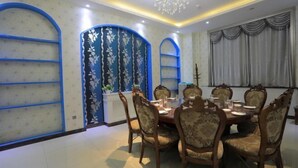 A dining room with a round table, six chairs, and a chandelier.