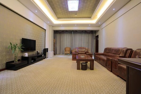 Una sala de estar moderna con un televisor de pantalla plana, sofás de cuero, una mesa de centro y un ventanal con cortinas.