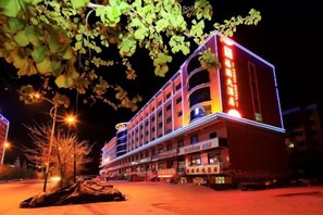 A multi-story hotel with a prominent sign, a well-lit entrance, and a parking area. - Furui Hotel (Fuyun)