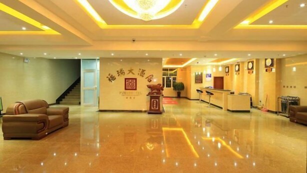 A hotel lobby with a polished floor, a reception desk, and a staircase.
