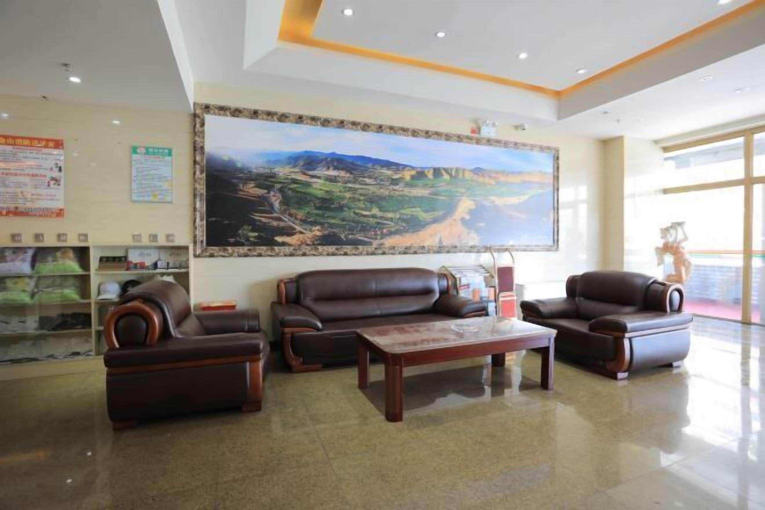 Eine großzügige Lobby mit einem großen Landschaftsgemälde, Ledersofas und einem Couchtisch.