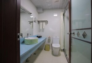 Un baño con encimera azul, un lavabo redondo, un inodoro y una cabina de ducha de vidrio.