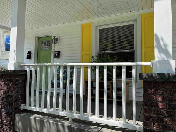 A porch with a white railing, a green door, and yellow trim. - The Yellow-Shuttered House apt B (Sharon)
