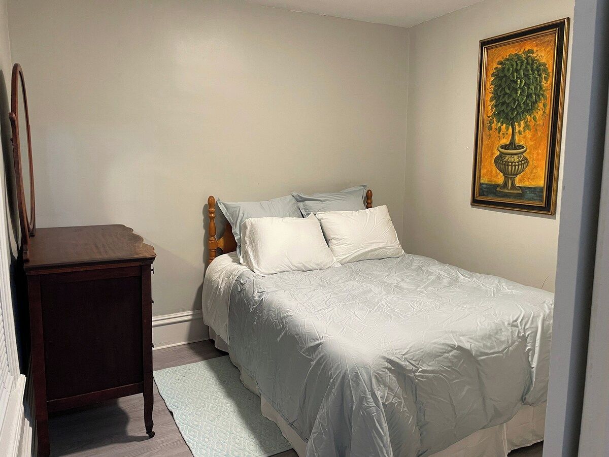Un dormitorio con una cama, una mesita de noche y un cuadro en la pared.