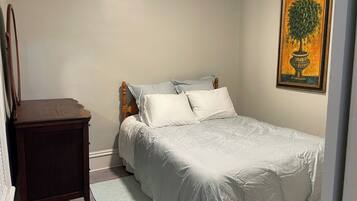 Un dormitorio con una cama, una mesita de noche y un cuadro en la pared.