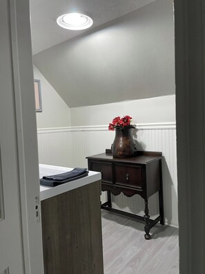 Une pièce avec un meuble en bois, une table en bois foncé ornée d’un vase de fleurs rouges et un radiateur blanc.
