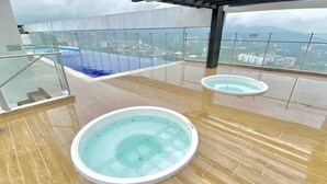 A rooftop terrace with two hot tubs and a view of a cityscape. - LUXURY APARTMENT IN THE GOLDEN MILE OF IBAGUÉ, COLOMBIA. (Ibagué)