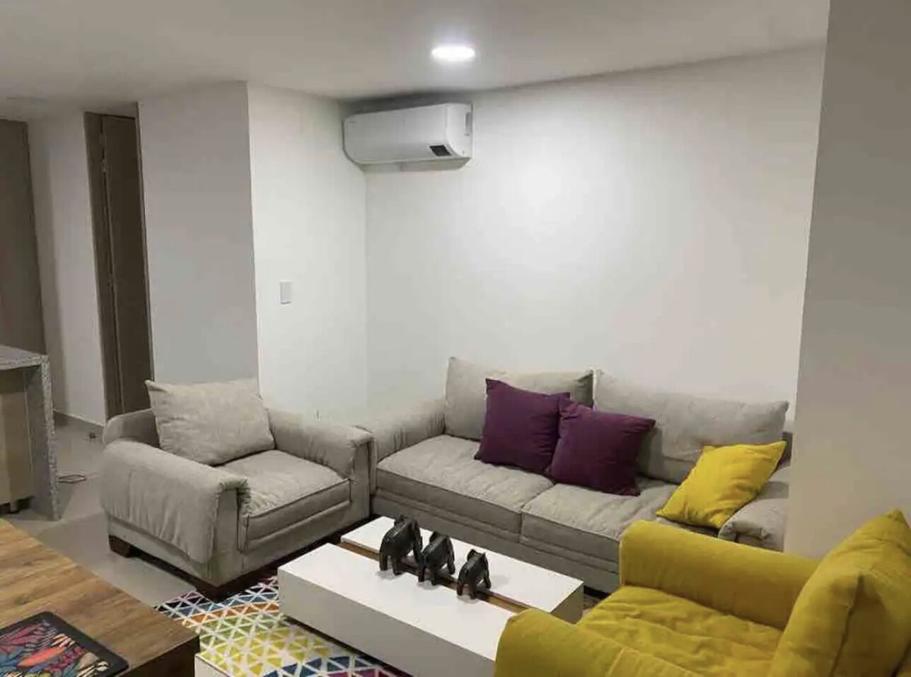 Una sala de estar con un sofá gris, un sillón amarillo y una mesa de centro con adornos.