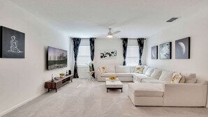 A modern living room with a sectional sofa, a coffee table, a TV, and artwork on the walls.