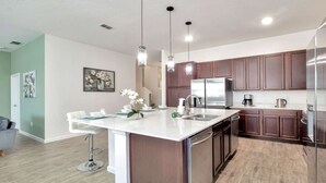 A modern kitchen with a central island, stainless steel appliances, and pendant lighting.